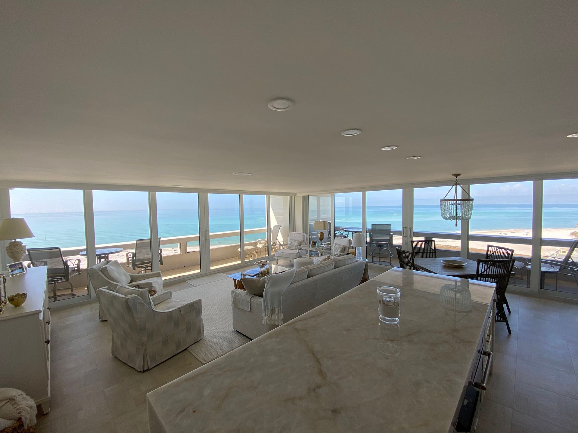 A large living room with a lot of windows overlooking the ocean.