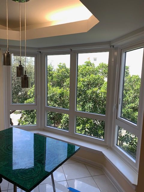 A dining room with a green table and lots of windows