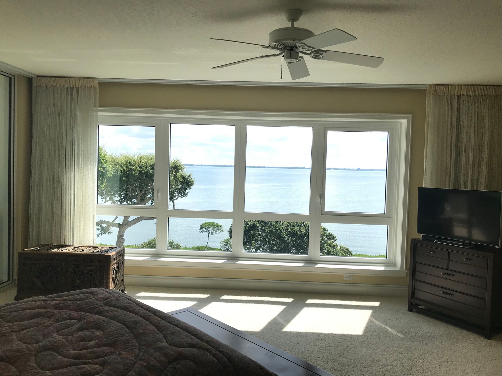A bedroom with a view of the ocean and a ceiling fan
