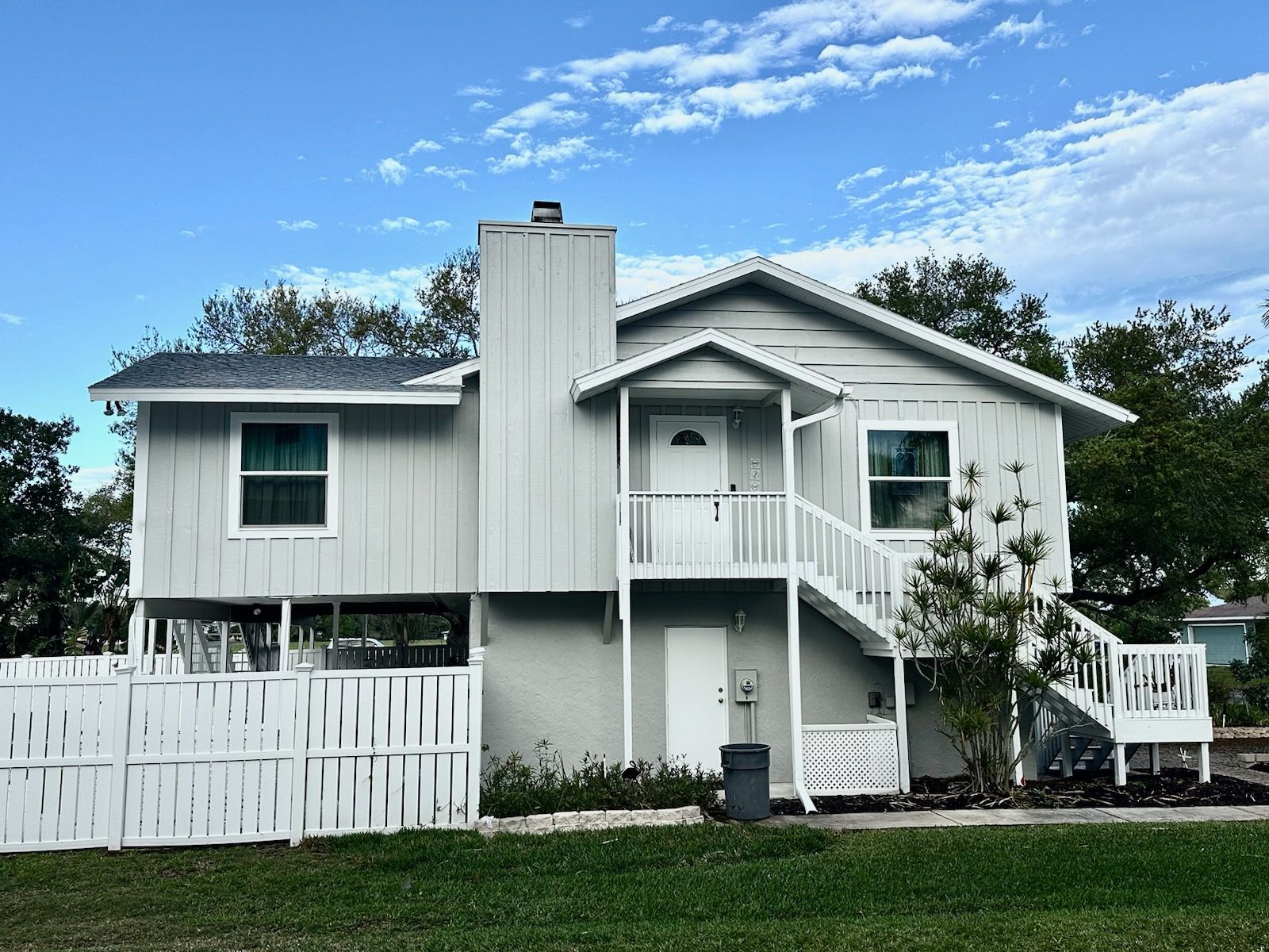 A large white house with stairs and a white fence