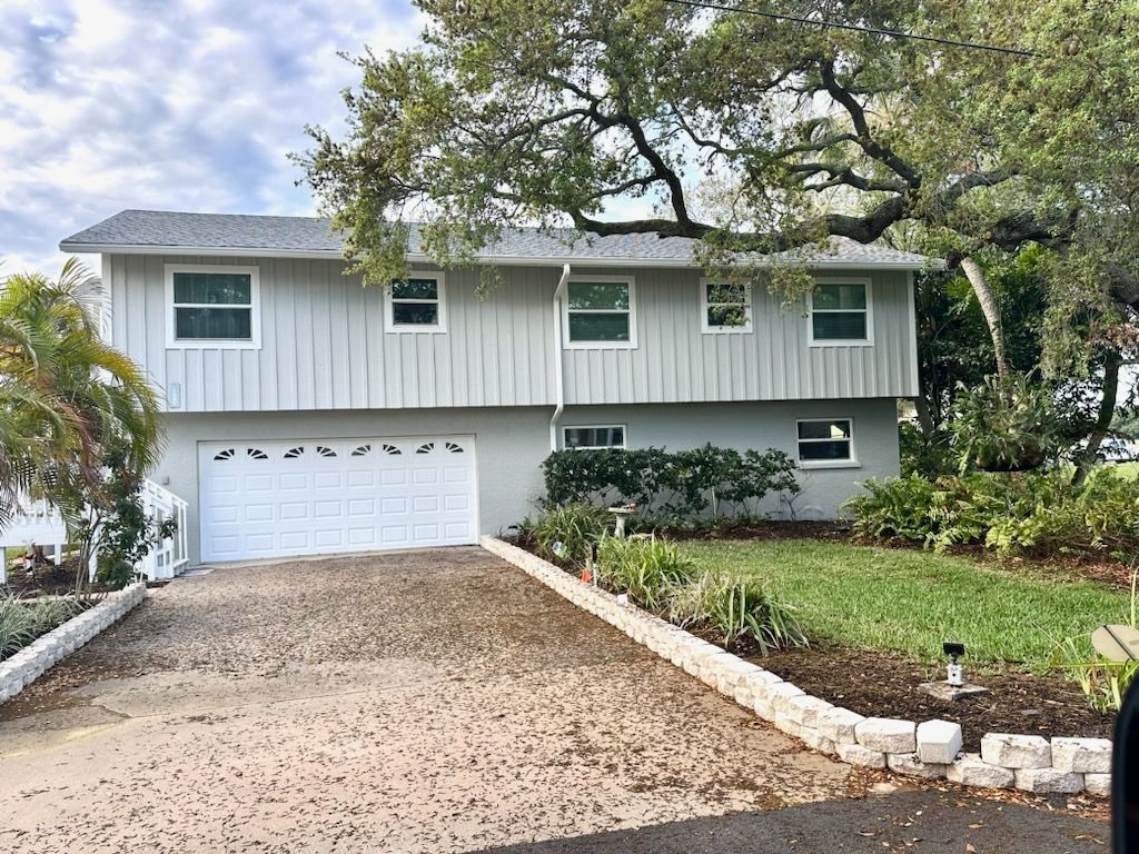 A white house with a white garage door and a gravel driveway.