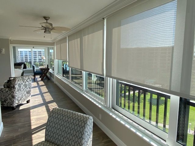 A living room with a lot of windows and a ceiling fan.