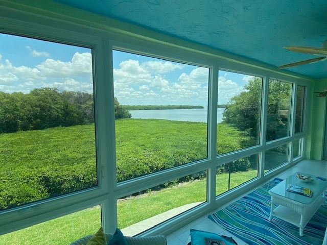 A screened in porch with a view of a lake.