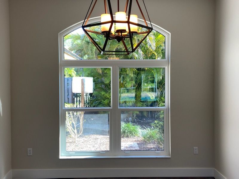 An empty room with a large window and a chandelier hanging from the ceiling.