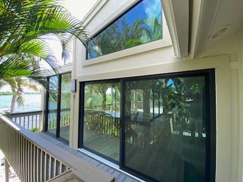 A house with sliding glass doors and a balcony overlooking a body of water.