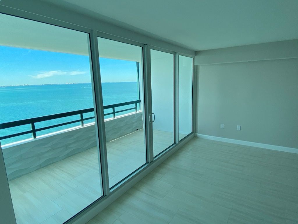 An empty room with a balcony overlooking the ocean.
