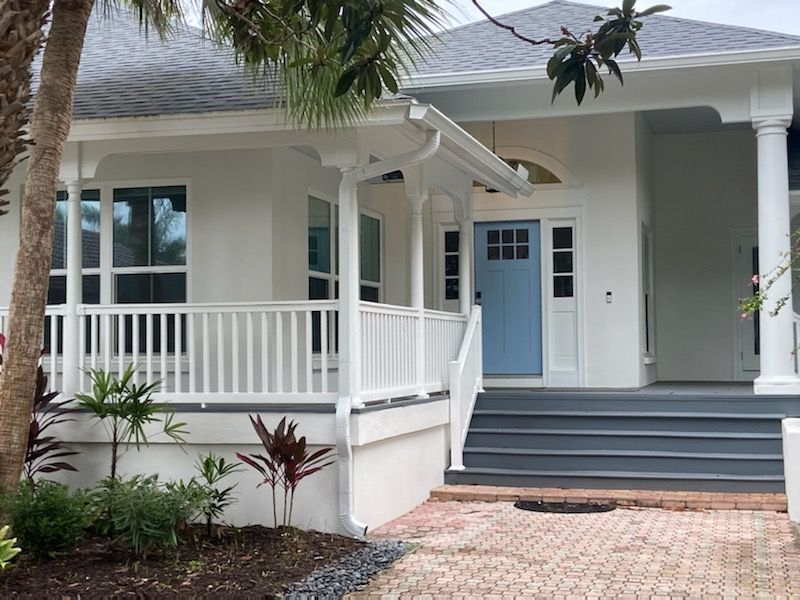 The front of a white house with a blue door and porch.