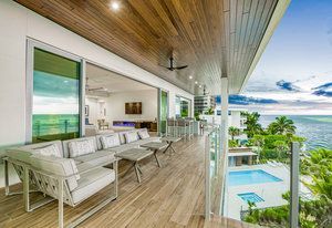 A large balcony with a view of the ocean and a swimming pool.