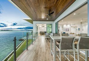 A large balcony with a table and chairs overlooking the ocean.