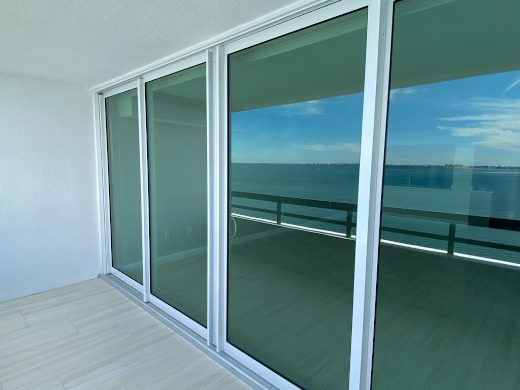 A balcony with sliding glass doors and a view of the ocean.