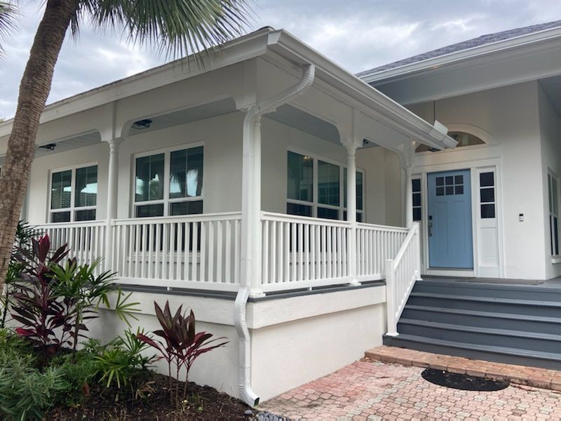 A white house with a blue door and a white porch
