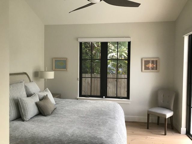 A bedroom with a bed a chair and a ceiling fan