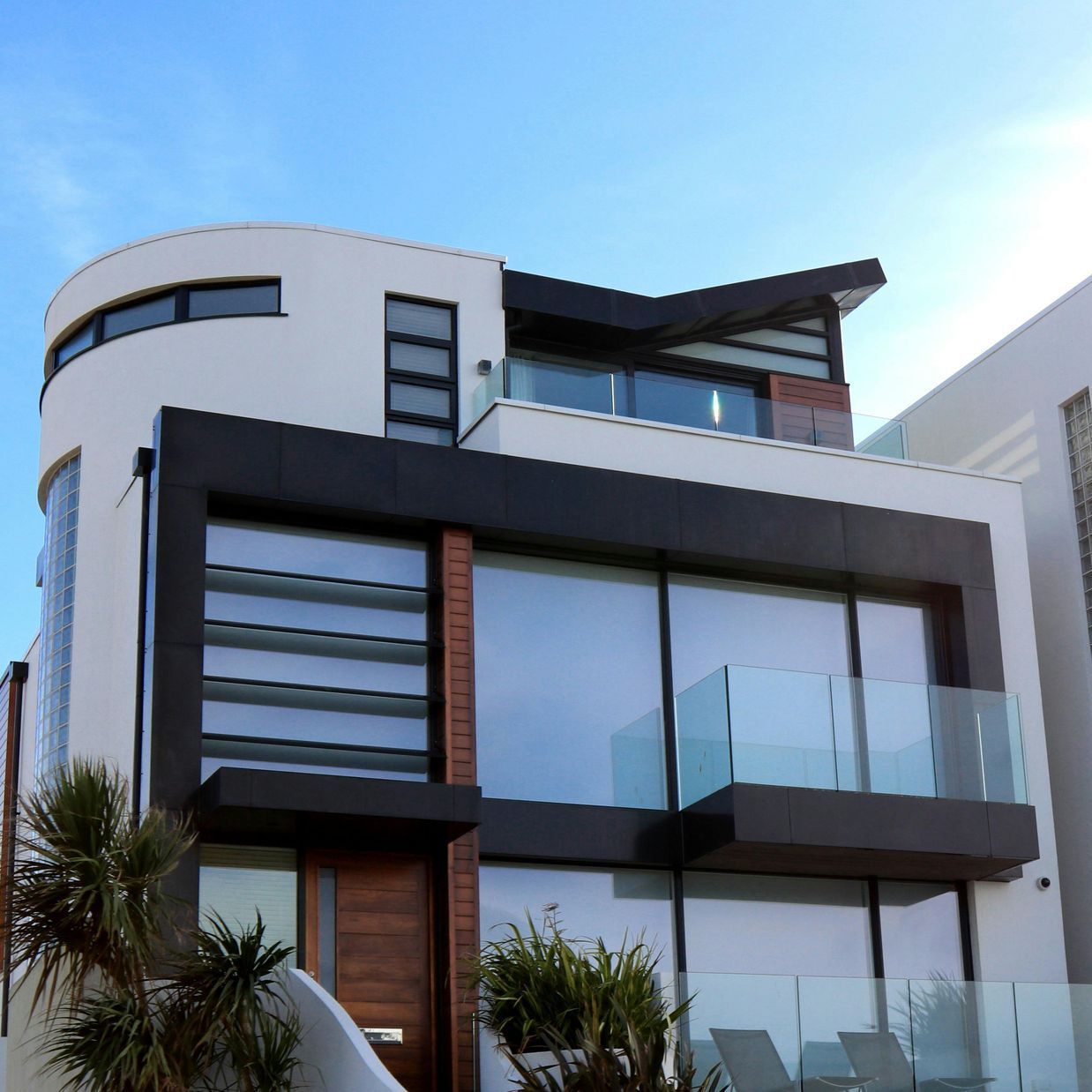 Modern white-and-gray contemporary house with large glass windows under a blue sky