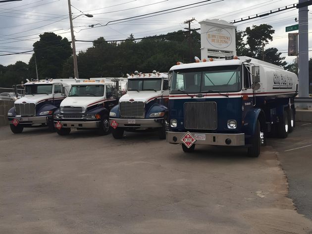 Parked fuel tanker trucks lined up in a lot on an overcast day.