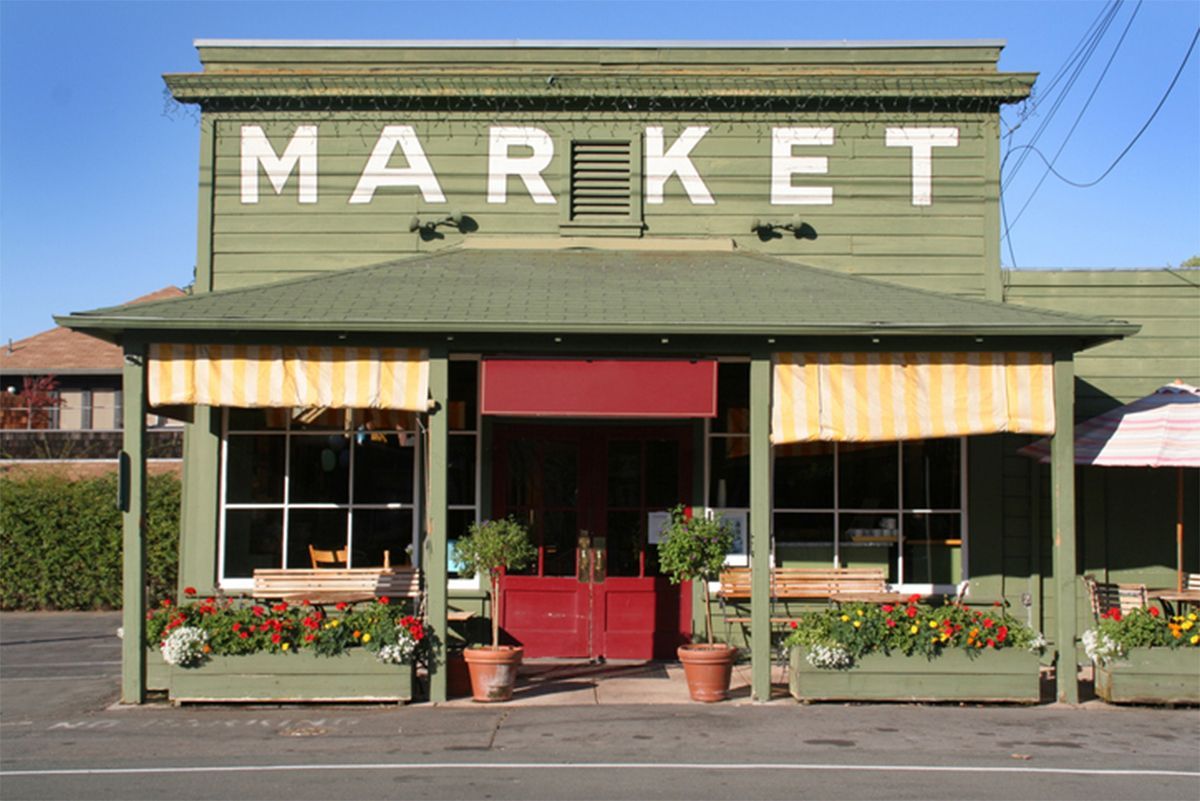 Green storefront with striped awnings and large “MARKET” sign above the entrance