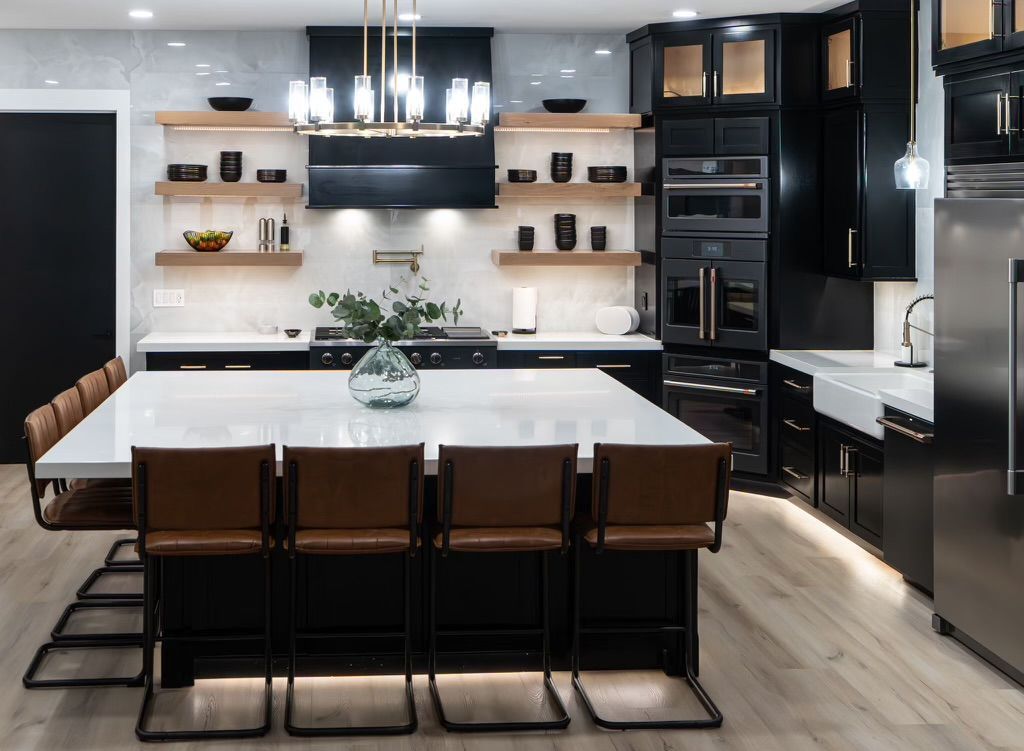 A kitchen with black cabinets, stainless steel appliances, and a large island.
