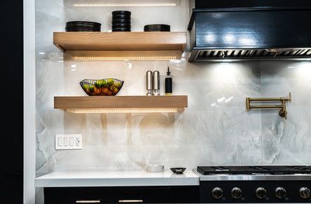A kitchen with a stove and a bowl of fruit on the shelves.
