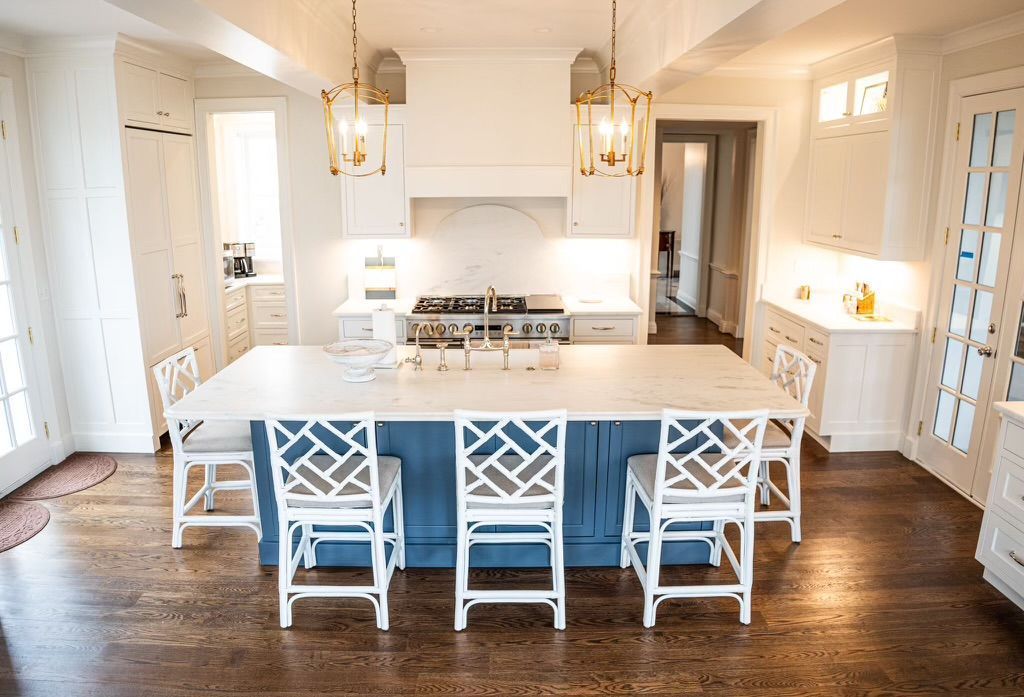 A kitchen with a blue island and white chairs.