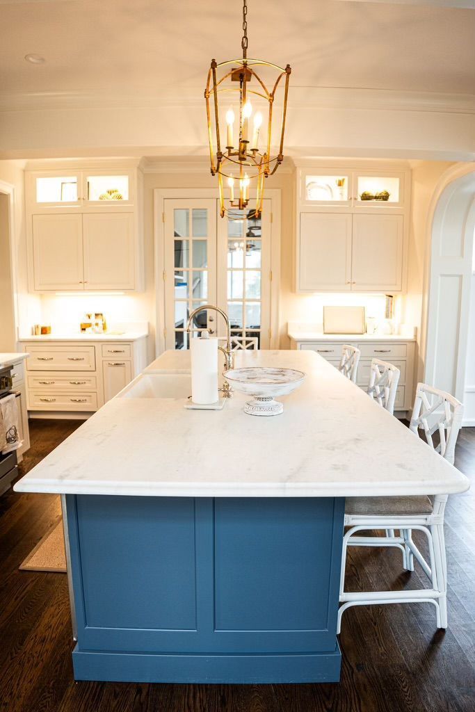 A kitchen with a large blue island and white cabinets.