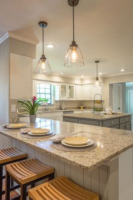 A kitchen with a granite counter top , stools , and plates on it.