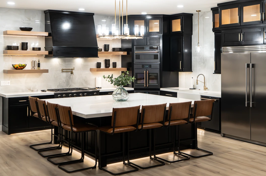A kitchen with black cabinets and stainless steel appliances and a large island.