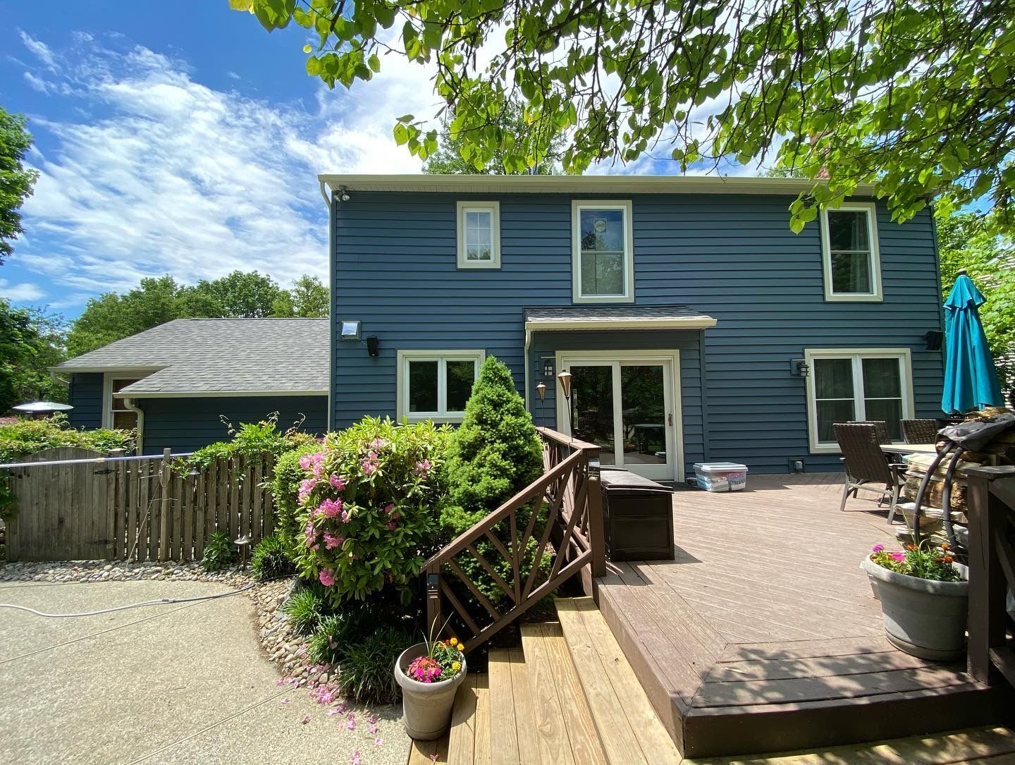 A large blue house with a deck and stairs in front of it.