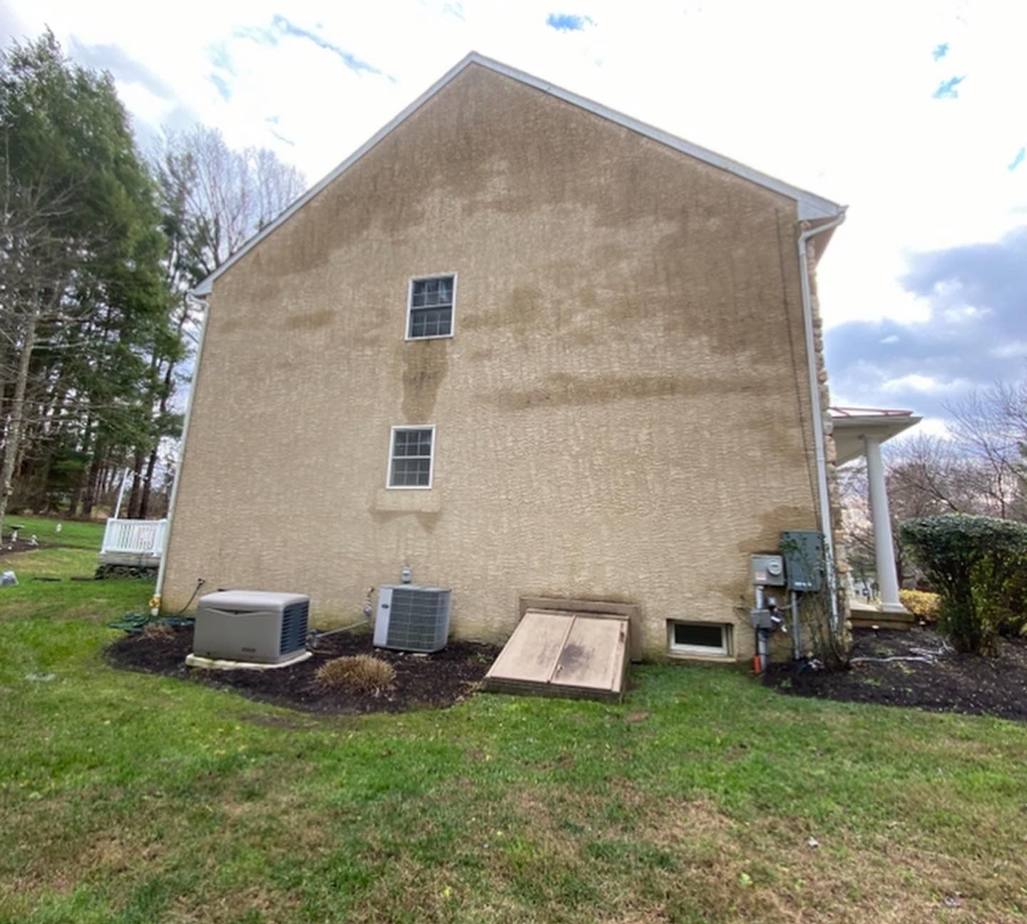 A large house with a lot of windows is sitting in the middle of a lush green field.