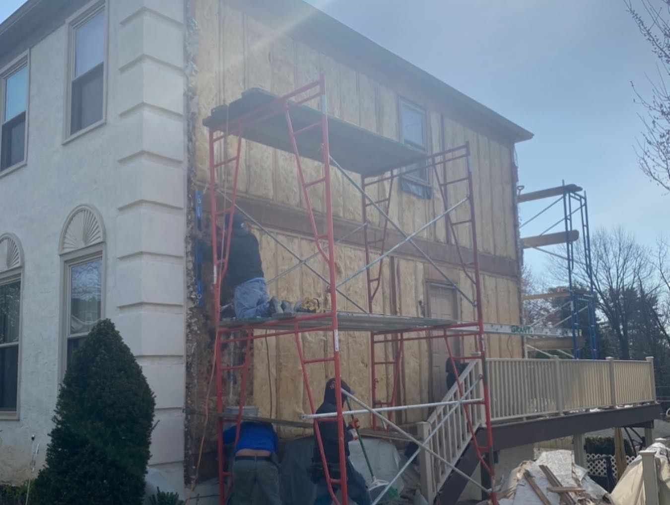 A man is standing on a scaffolding on the side of a house.