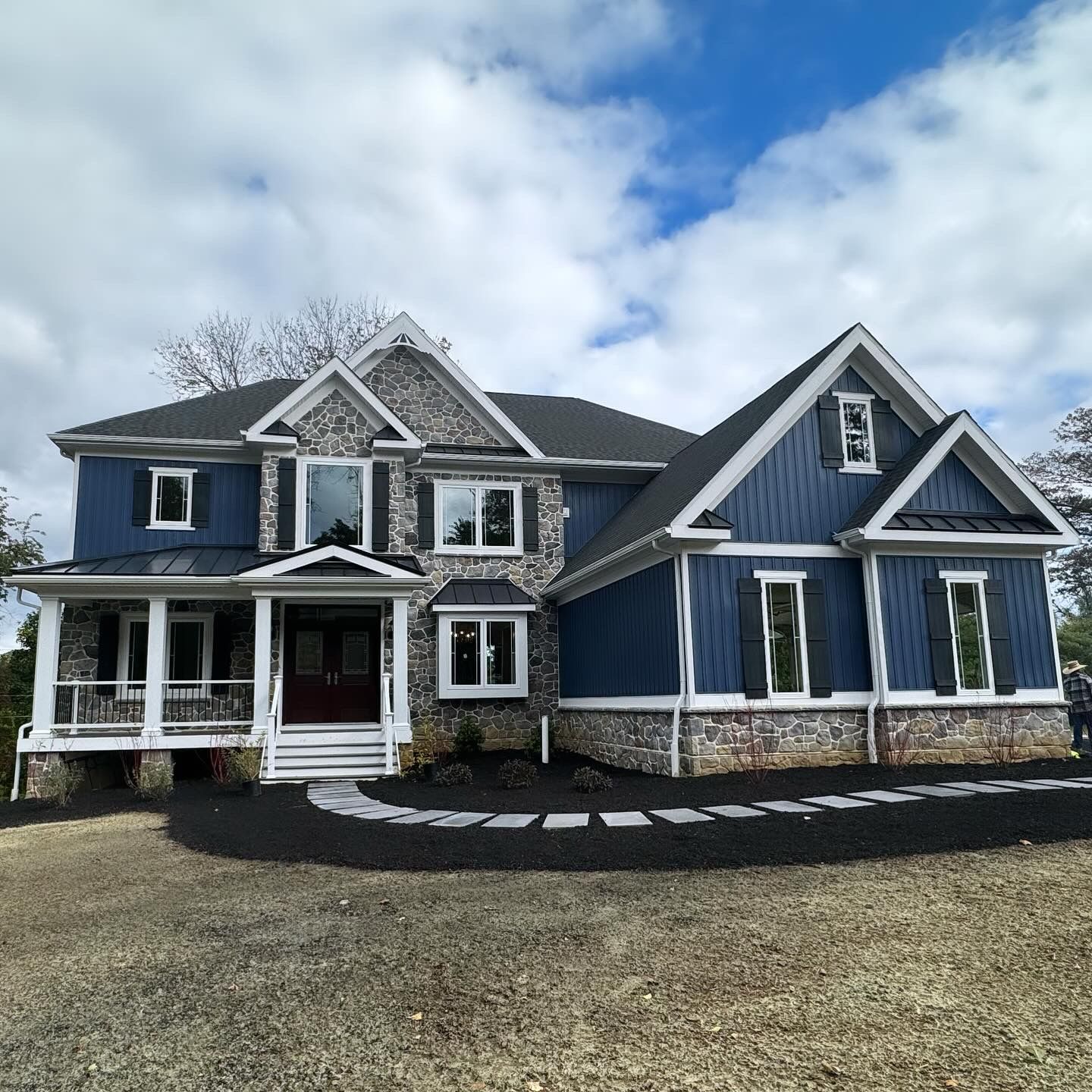 A large blue house with a black roof and white trim
