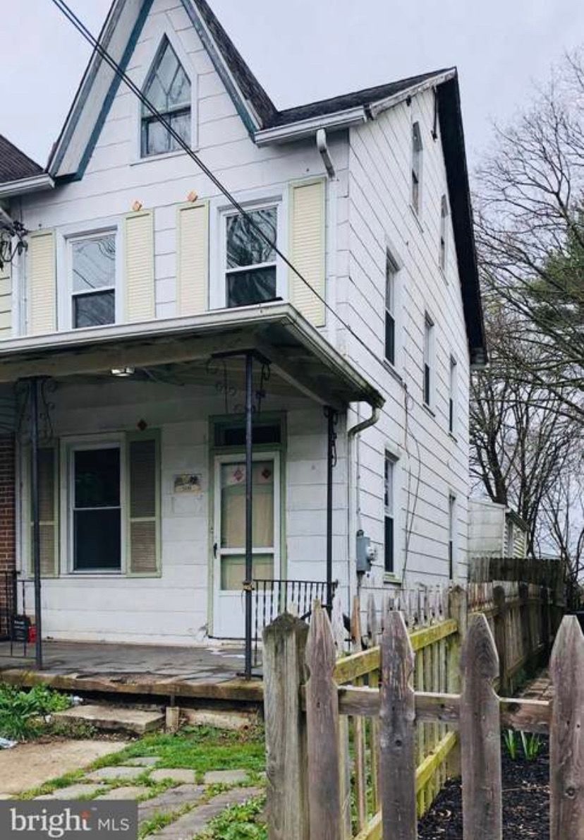 A white house with a wooden fence in front of it.