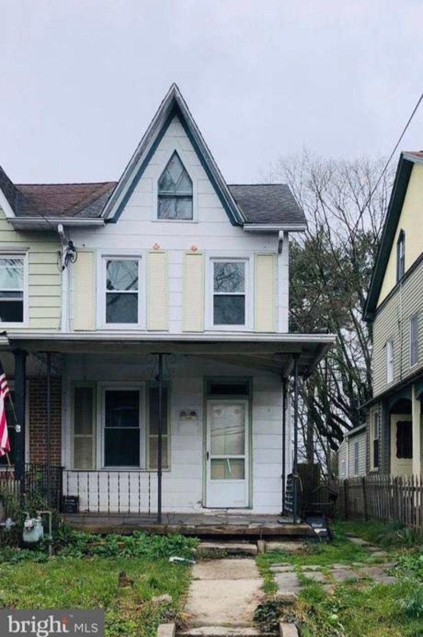 A white house with a gray roof is for sale.