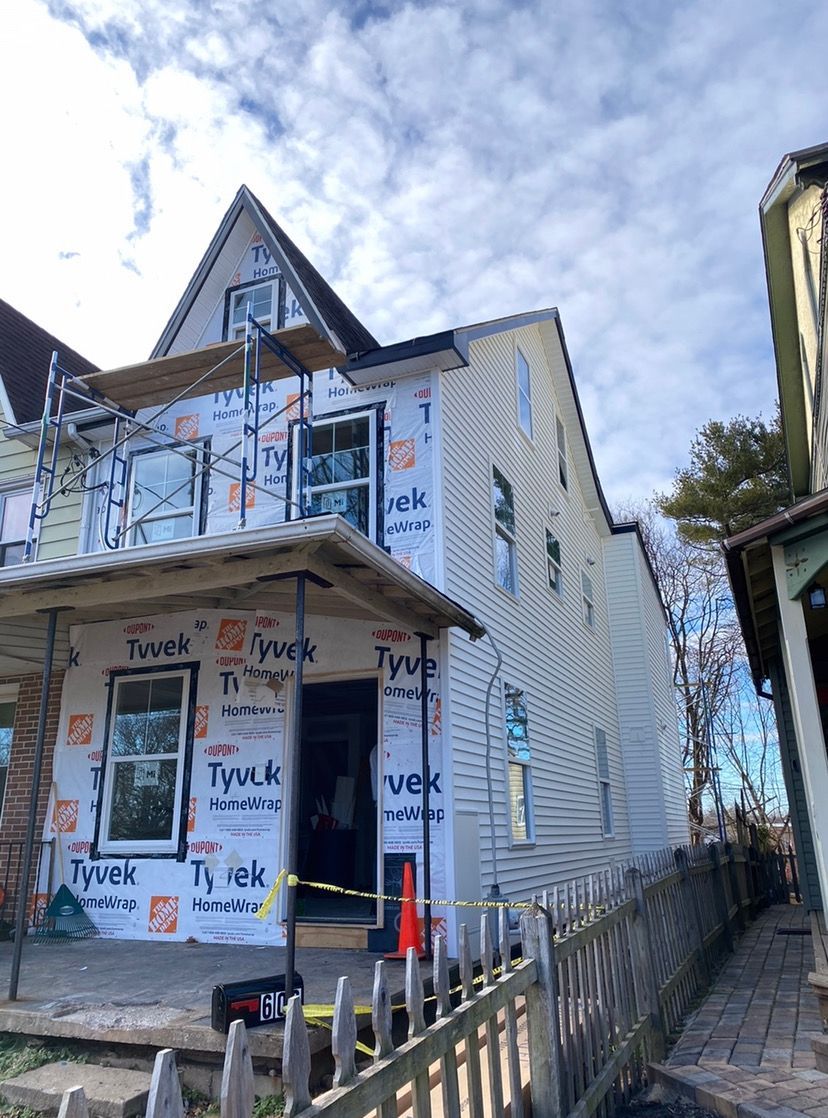 A house is being remodeled with scaffolding and a fence.