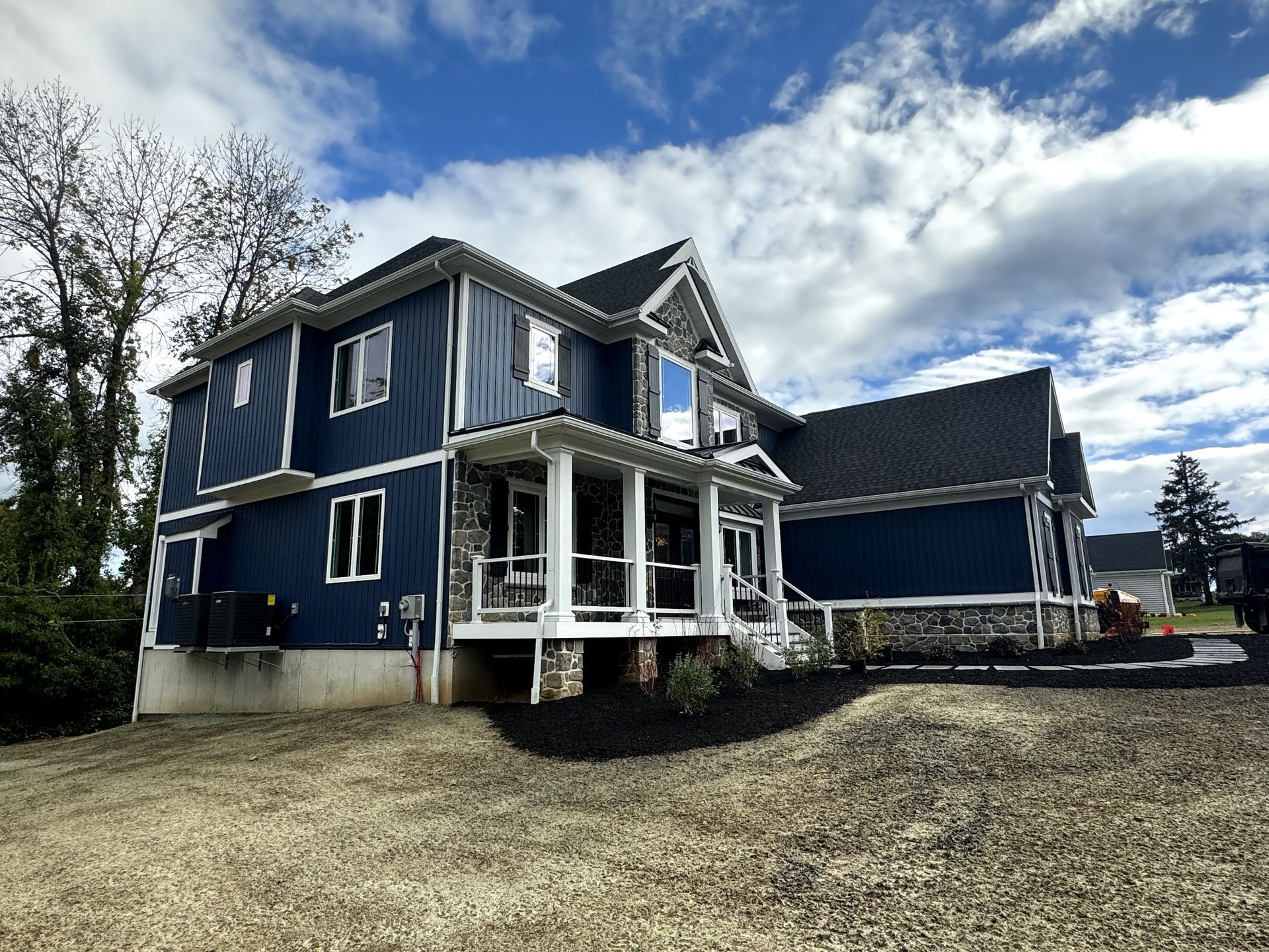 A large blue house with a porch and a blue sky in the background