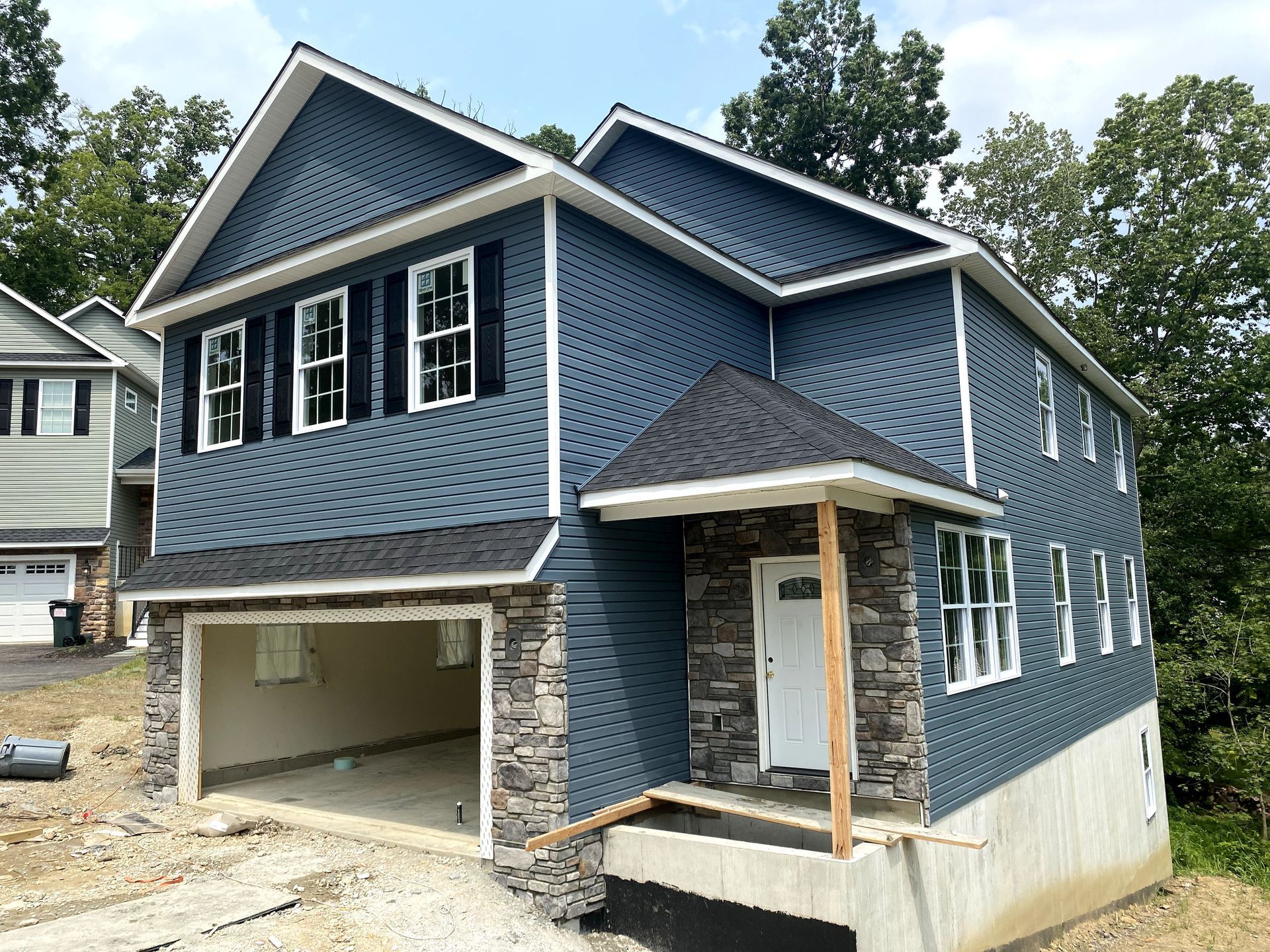 A blue house with a garage underneath it is being built.