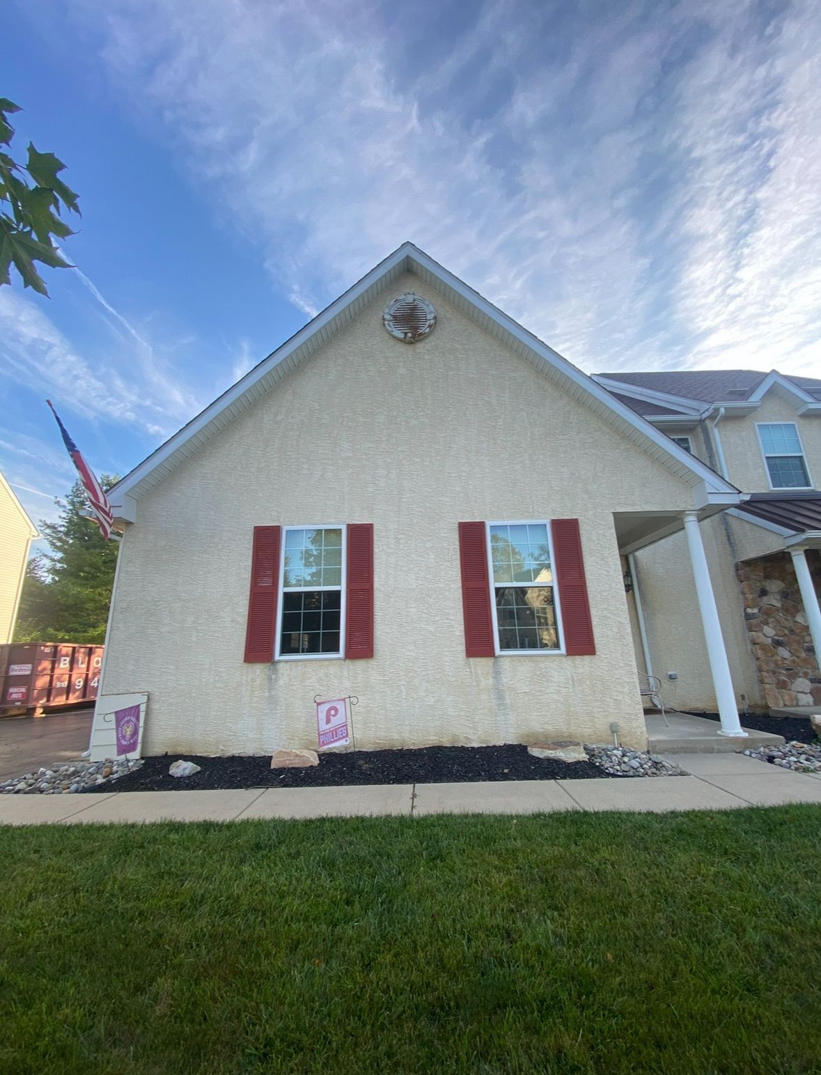 A white house with red shutters on the windows and a blue sky in the background.