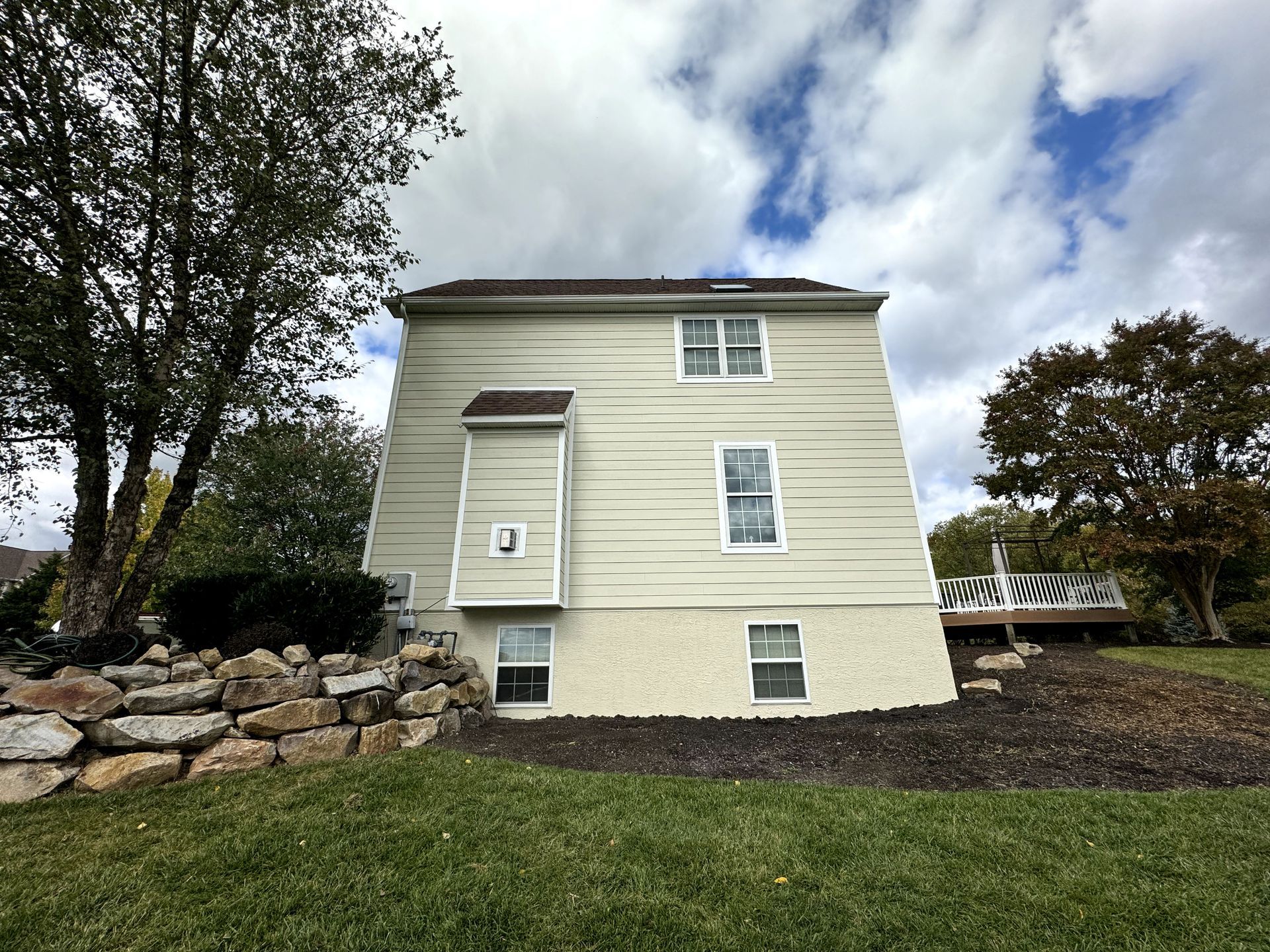 A large house with a lot of windows is sitting on top of a lush green field.