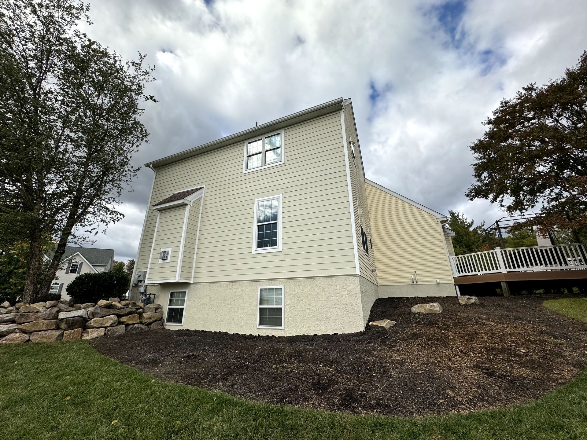 The back of a house with a deck and a lot of windows
