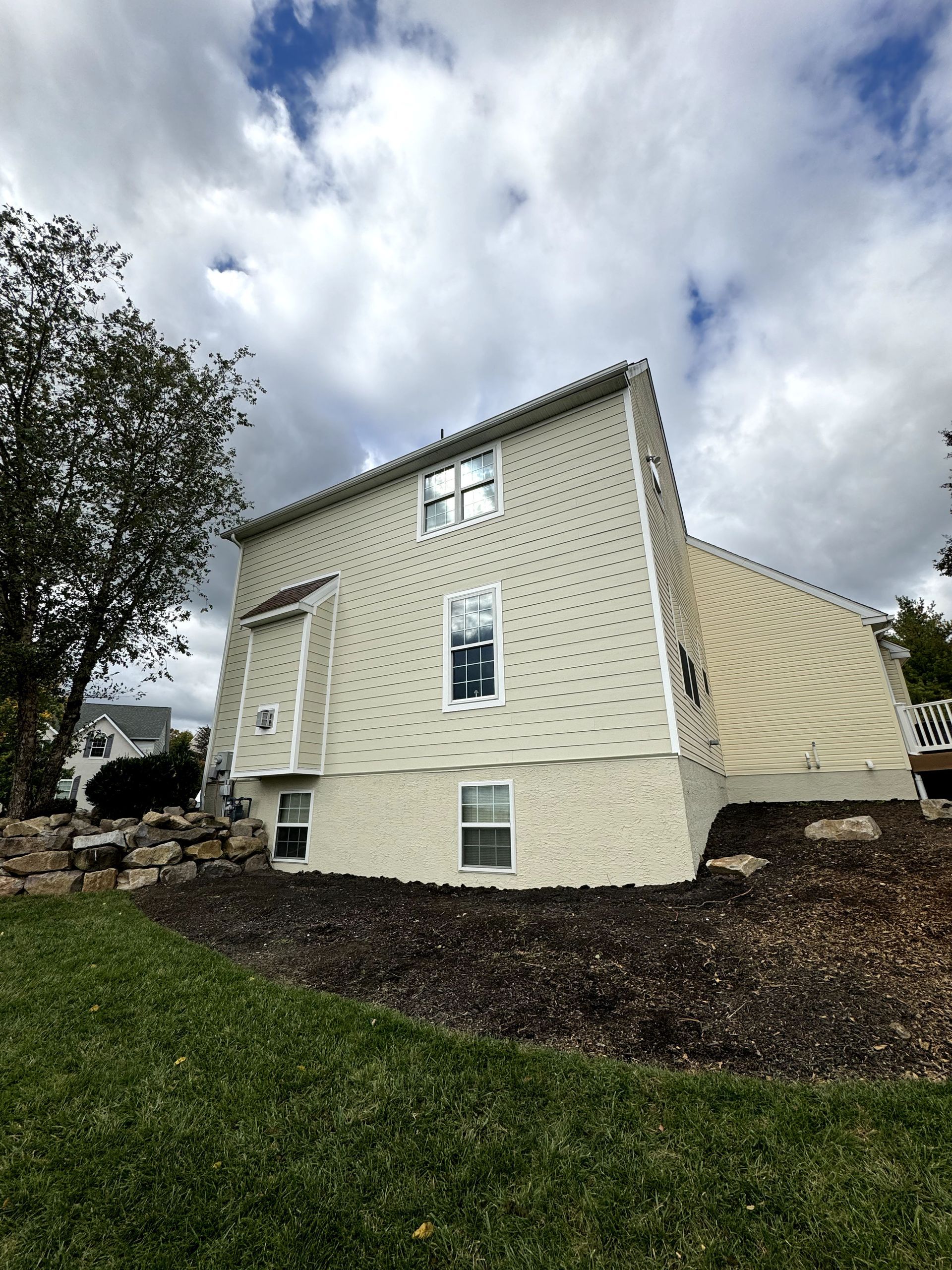 A large white house with a lot of windows is sitting on top of a lush green hillside.
