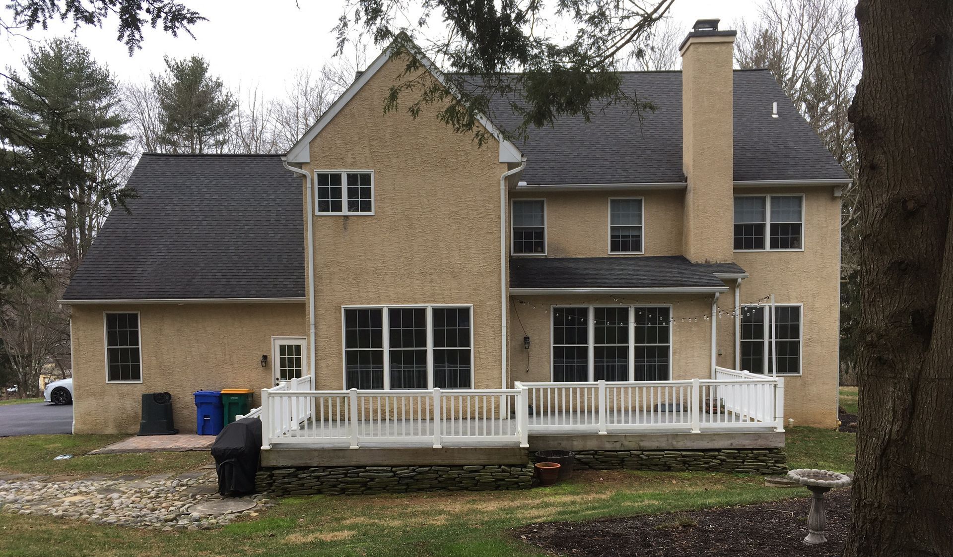 A large house with a white deck and a black roof