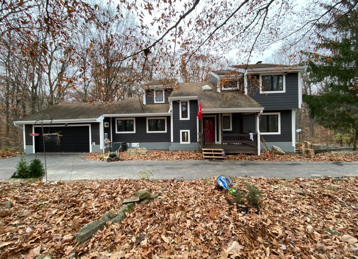 A large house with a lot of leaves on the ground in front of it.