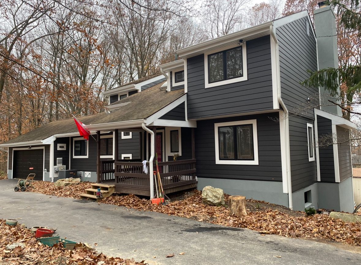 A large house with a lot of leaves on the ground in front of it.
