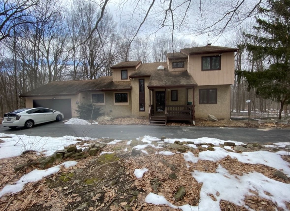 A large house with a car parked in front of it in the snow.