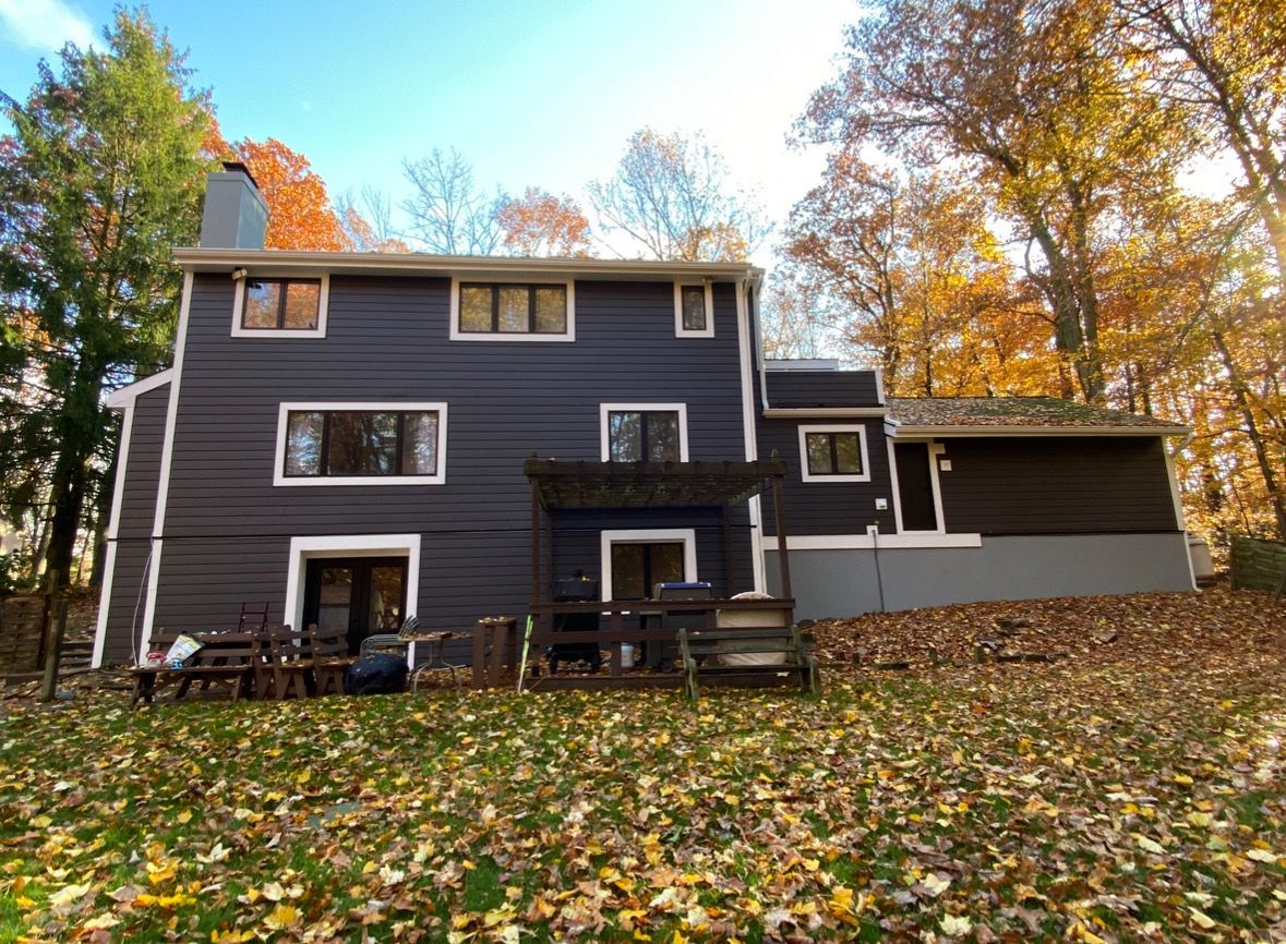 The back of a house with a lot of leaves on the ground