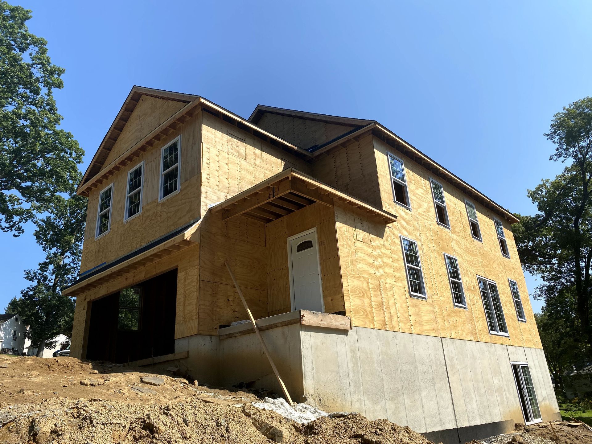 A house under construction is sitting on top of a dirt hill.