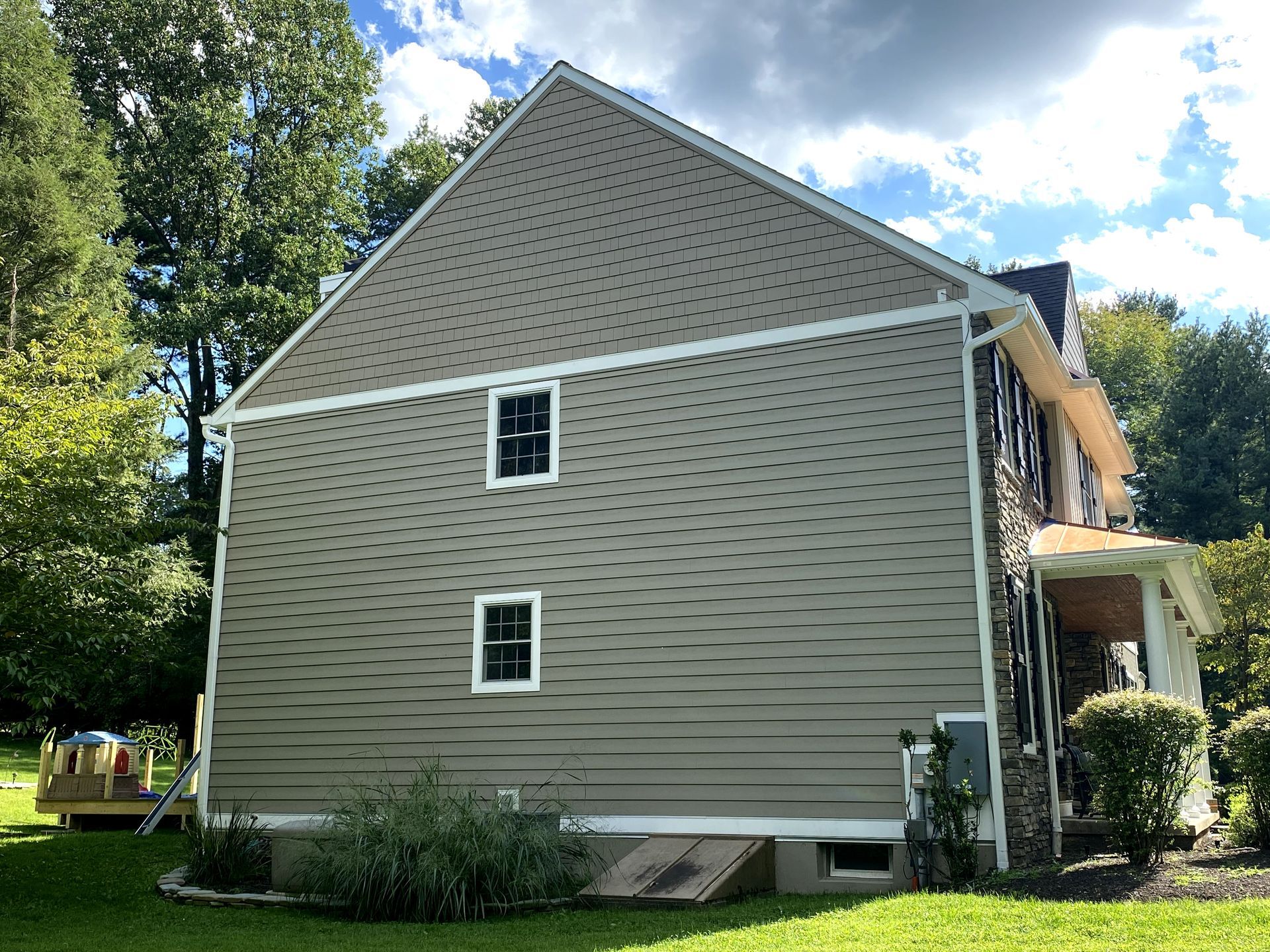 A large house with a lot of windows is sitting on top of a lush green field.