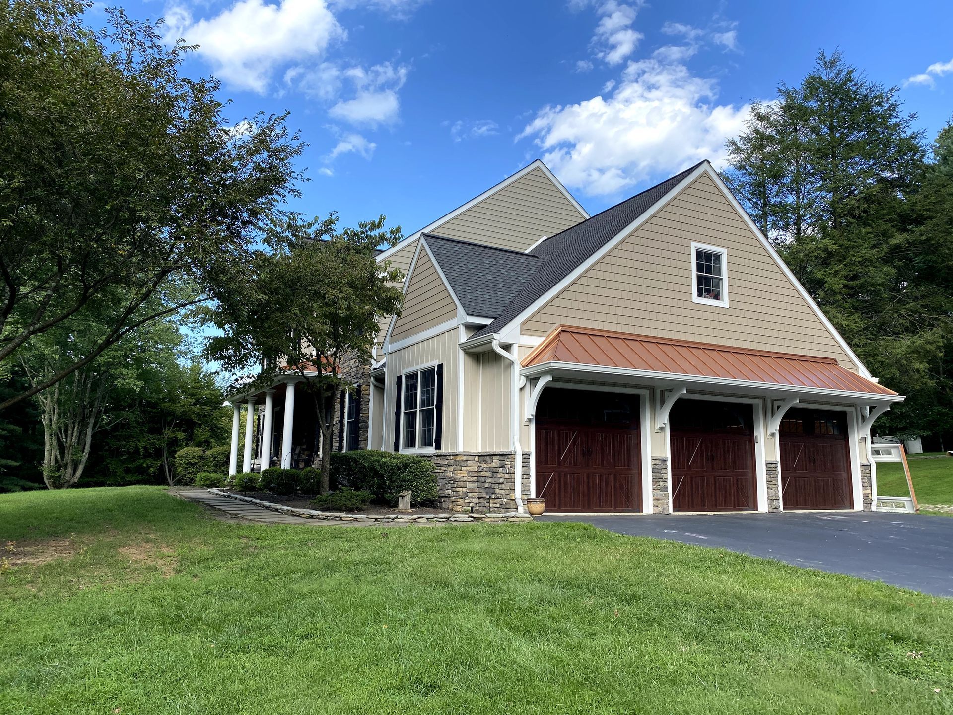 A large house with two garage doors is sitting on top of a lush green field.