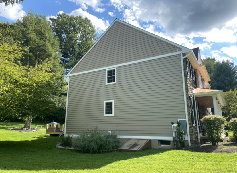 A large house with a lot of windows is sitting on top of a lush green lawn.