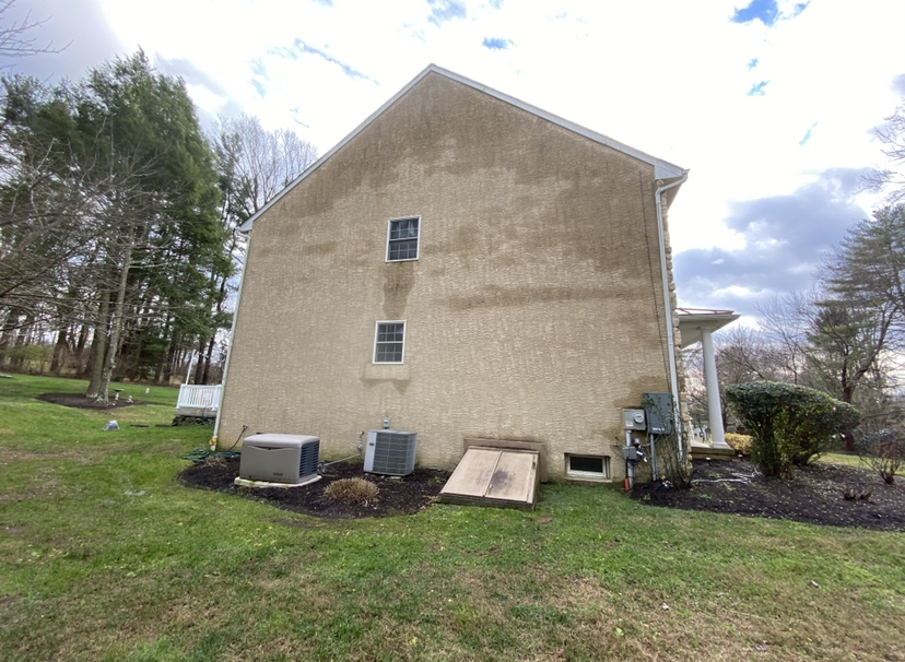 A large house with a lot of windows is sitting on top of a lush green field.