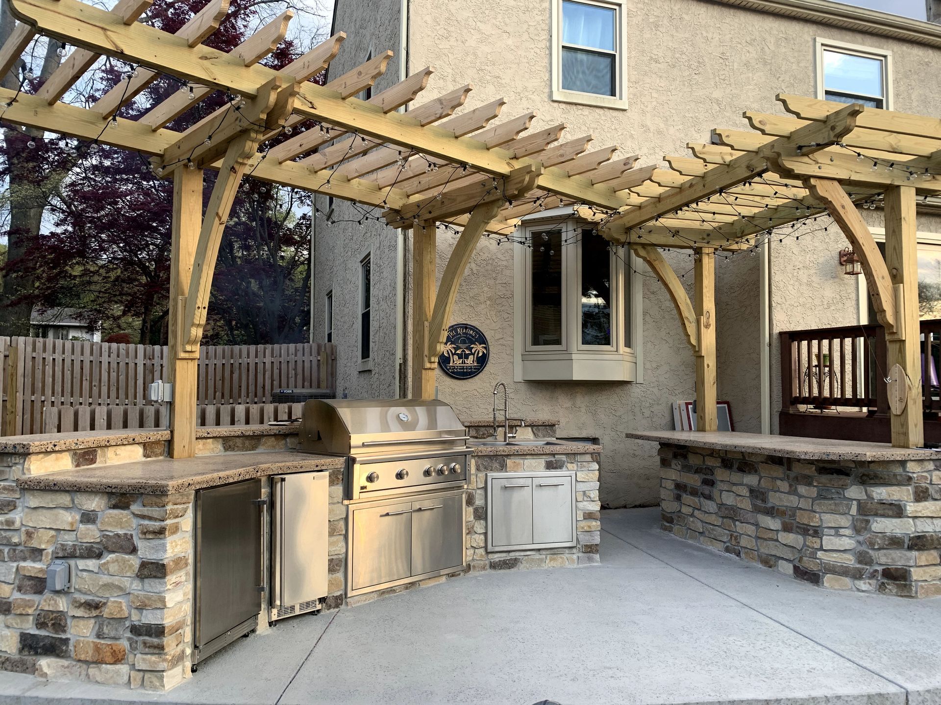 A large outdoor kitchen with a pergola over it