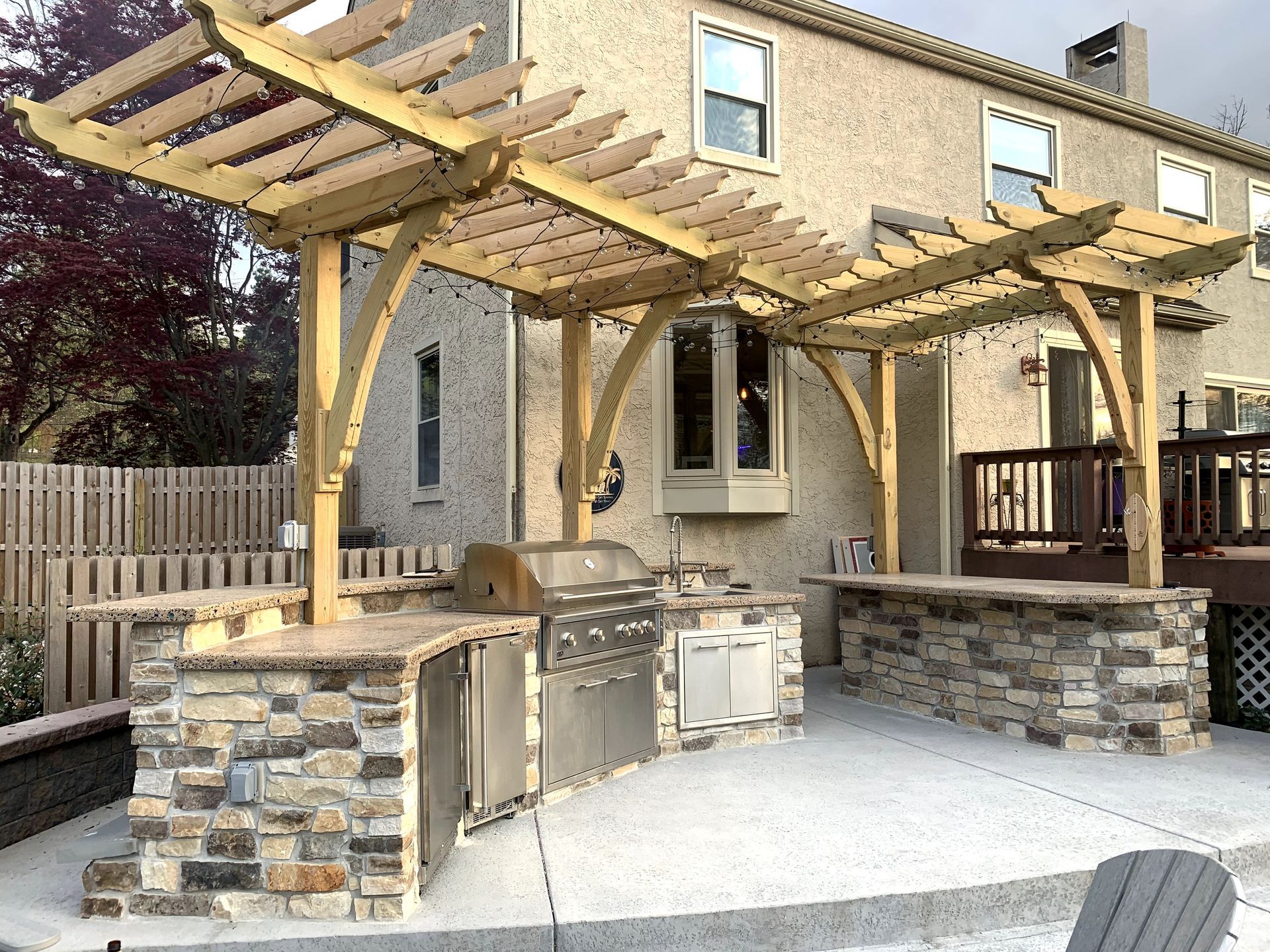 A large outdoor kitchen with a wooden pergola over it.